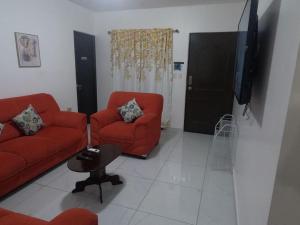 sala de estar con 2 sillas rojas y TV de pantalla plana en MADDY Free Wi-Fi, AC in ea Bedrooms, Private Community!, en San Miguel