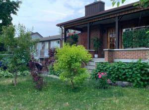 una casa con alcuni cespugli e alberi nel cortile di Havre chez Guylaine a Laval