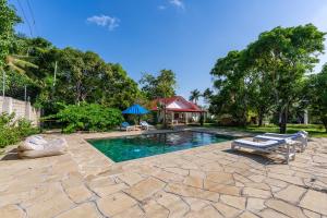 una piscina con due sedie a sdraio e una casa di Hibiscus Home&Apartments a Galu