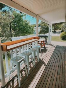 eine Veranda mit einer Bank und Hockern auf einer Terrasse in der Unterkunft Eight Acres Lakes Entrance in Lakes Entrance