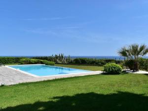 a swimming pool in a yard with the ocean in the background at Villa Les Issambres, 6 pièces, 10 personnes - FR-1-768-27 in Les Issambres