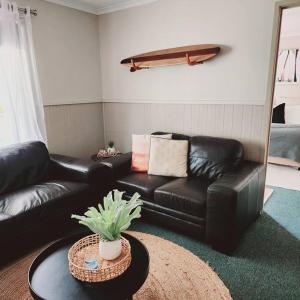 a living room with a black leather couch and a table at Eight Acres Lakes Entrance in Lakes Entrance