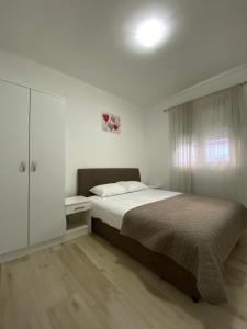 a white bedroom with a bed and a white cabinet at P&M Ilic in Herceg-Novi