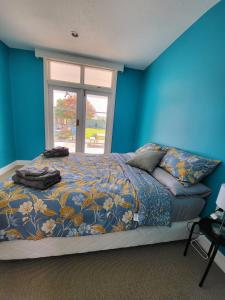 a bedroom with a bed with blue walls and a window at Ashburton Family Home in Ashburton