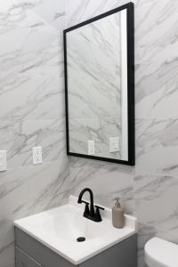 ein weißes Badezimmer mit einem Waschbecken und einem Spiegel in der Unterkunft Misbau home in Brooklyn