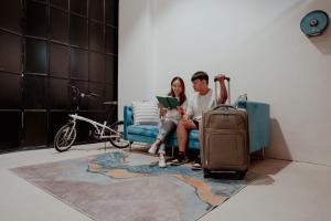新加坡的住宿－Code Hostel Singapore，男人和女人坐在椅子上,带着手提箱