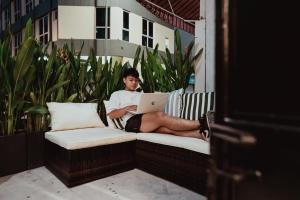 a man sitting on a couch with a laptop at Code Hostel Singapore in Singapore
