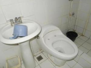 a bathroom with a white toilet and a sink at Abrassi hotel tayum abra in Bangued