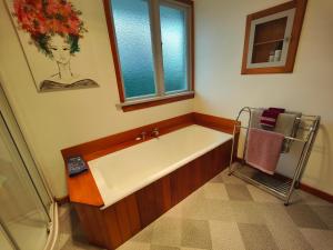een badkamer met een bad en een raam bij Peaceful by the Park in Invercargill