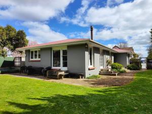 a small white house with a grass yard at Peaceful by the Park in Invercargill