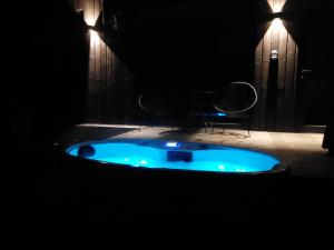 bañera azul en una habitación oscura con silla en BRENDIS -'Virš Ąžuolų' - Forest SPA - FREE jacuzzi en Paplatelė