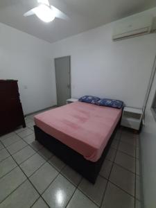 Un dormitorio con una cama con una manta rosa. en Capao Canoa - Próximo Mar Centro, en Capão da Canoa