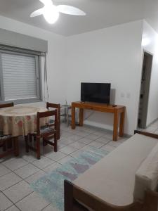 a living room with a tv and a table at Capao Canoa - Próximo Mar Centro in Capão da Canoa