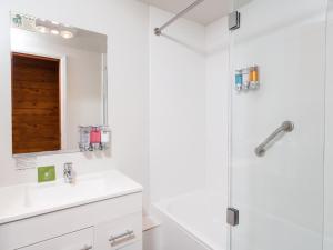 La salle de bains blanche est pourvue d'un lavabo et d'une douche. dans l'établissement Leisure Inn Penny Royal Hotel & Apartments, à Launceston
