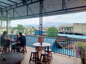 a couple of people sitting at tables on a balcony at OYO 93333 Rama Home Stay in Jayapura