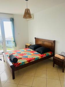 ein Bett mit farbenfroher Bettdecke in einem Schlafzimmer in der Unterkunft Ocean View Chambre in Saint-Leu