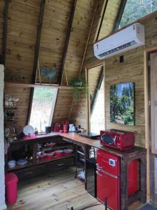 eine Küche in einem Blockhaus mit einem roten Herd in der Unterkunft Chalé Alcântara in São Pedro de Alcântara