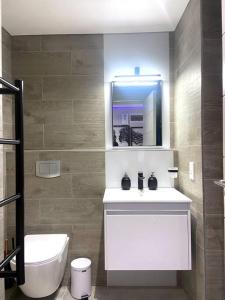 a bathroom with a sink and a toilet and a mirror at Luxury apt Cape Town City Centre- walk to CTICC in Cape Town