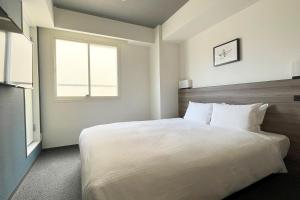 Un dormitorio con una gran cama blanca y una ventana en Best Western Sapporo Odori Koen, en Sapporo