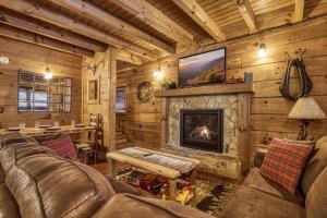 a living room with a fireplace in a log cabin at Bridgewood Cabin- New Listing - Hot Tub, Pool Table, Free Attraction Tickets in Pigeon Forge