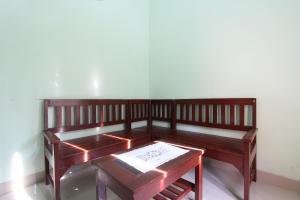 eine Holzbank mit einem Tisch in einem Zimmer in der Unterkunft SPOT ON 93324 Hadi Homestay Syariah in Sleman
