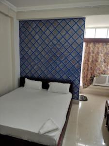 a bedroom with a bed with a blue accent wall at HOTEL EAST INN DIMAPUR in Dimāpur