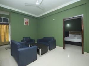 Pokój z 2 niebieskimi krzesłami i łóżkiem w obiekcie HOTEL EAST INN DIMAPUR w Dimapur