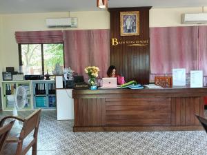 a woman sitting at a reception desk with a laptop at Baan Suan Villas Resort in Ban Suan