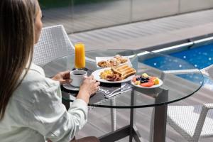 a woman sitting at a glass table with a plate of food at Holiday Inn Express - Iquique, an IHG Hotel in Iquique