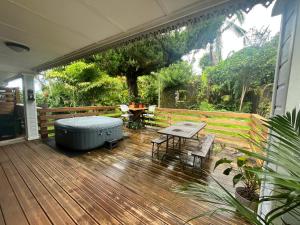 een terras met een hot tub en een tafel en stoelen bij La Trinité, charme historique du Sud Sauvage in Saint-Philippe