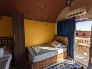 a bedroom with two beds in a room with a balcony at Abu simbel Nubian Guest House in Abu Simbel