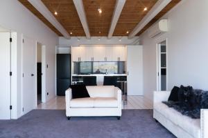 a living room with a white couch and a kitchen at Te Wai • Luxe @ The Lake • in Queenstown