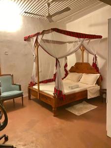 een slaapkamer met een hemelbed en een stoel bij SAFARI in Stone Town