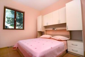 - une chambre avec des murs roses et un lit avec des draps roses dans l'établissement Apartments Sunny - quiet and relaxing, à Makarska