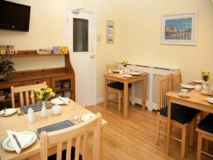sala de estar con mesas, sillas y TV en The Meltham Guesthouse Scarborough, en Scarborough