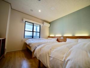 dwa łóżka w pokoju z oknem w obiekcie Hotel Ishigaki and Chikonkiya w mieście Ishigaki