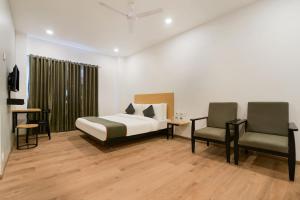 ein Schlafzimmer mit einem Bett und zwei Stühlen darin in der Unterkunft Super Townhouse 217 The Awadh Airport Near Chaudhary Charan Singh International Airport in Bijnaur