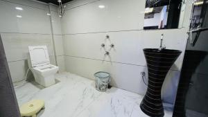 PALLAV GUEST HOUSE في اوجاين: حمام ابيض مع مرحاض ومغسلة