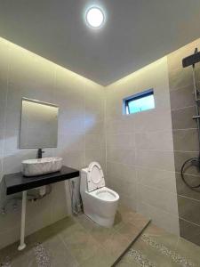 a bathroom with a toilet and a sink and a mirror at Welcome to Sarmax Homestay in Kuching