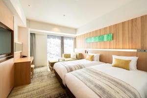 a hotel room with two beds and a flat screen tv at Hotel GrandBach Sendai in Sendai