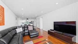 a living room with a black leather couch and a flat screen tv at Seapoint 109 in Mandurah