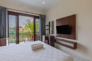 een slaapkamer met een bed, een televisie en een balkon bij Sedana Cottage in Canggu