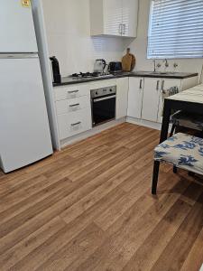 a kitchen with white cabinets and a wooden floor at Family Oasis in Adelaide in Bowden