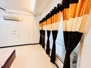 PALLAV GUEST HOUSE في اوجاين: غرفة بها ستائر سوداء و برتقالية ونافذة