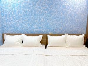 a bed with white pillows against a blue wall at Milan Homestay - Milanesa Hotel and Apartment in Vung Tau