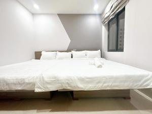 a white bed in a white room with a white mattress at Milan Homestay - Milanesa Hotel and Apartment in Vung Tau