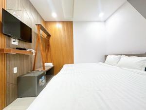 a bedroom with a white bed and a tv at Milan Homestay - Milanesa Hotel and Apartment in Vung Tau