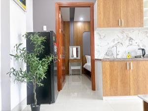a kitchen with a black refrigerator and a plant at Milan Homestay - Milanesa Hotel and Apartment in Vung Tau