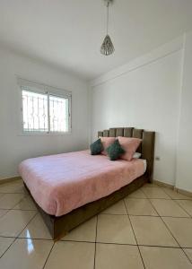 a bedroom with a bed with pink sheets and a window at Quartier Administratif in Tetouan