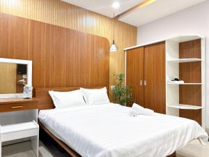 a bedroom with a large white bed and wooden walls at Milan Homestay - Milanesa Hotel and Apartment in Vung Tau